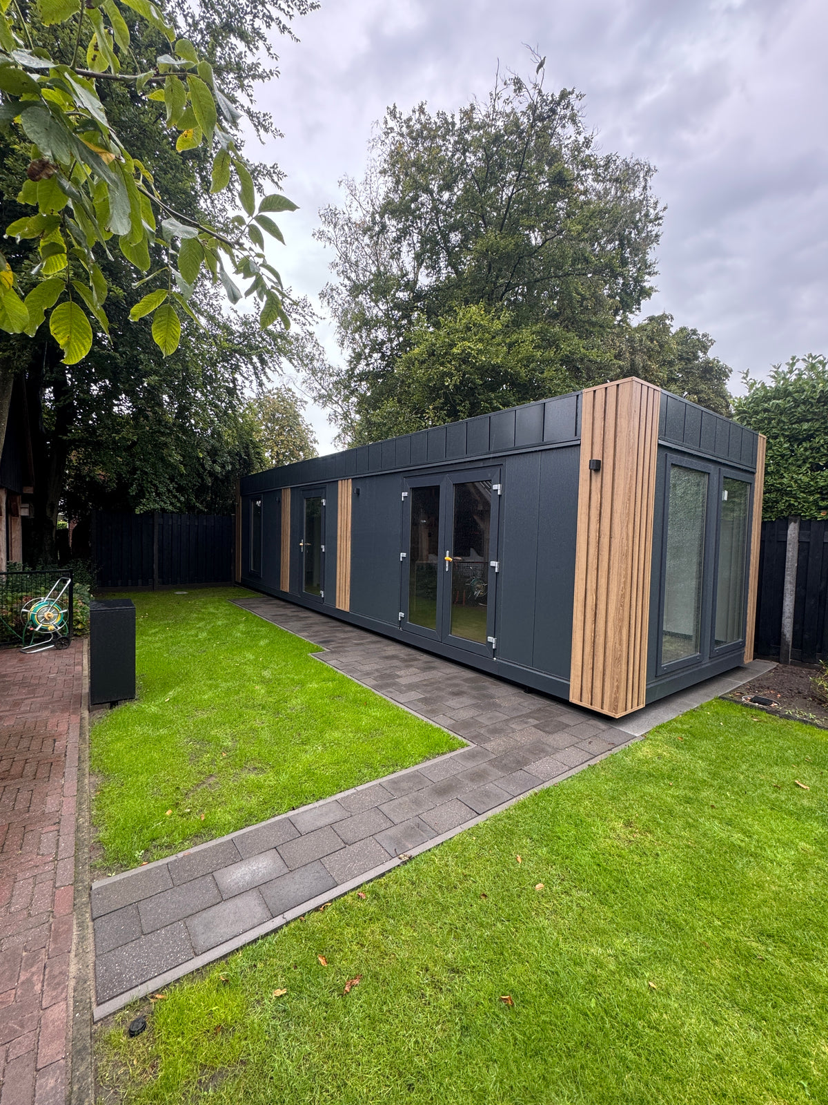 Gerealiseerde woonunit van 11 × 3,2 meter in Aalten met donkere gevel, houten accenten, complete keuken en badkamer