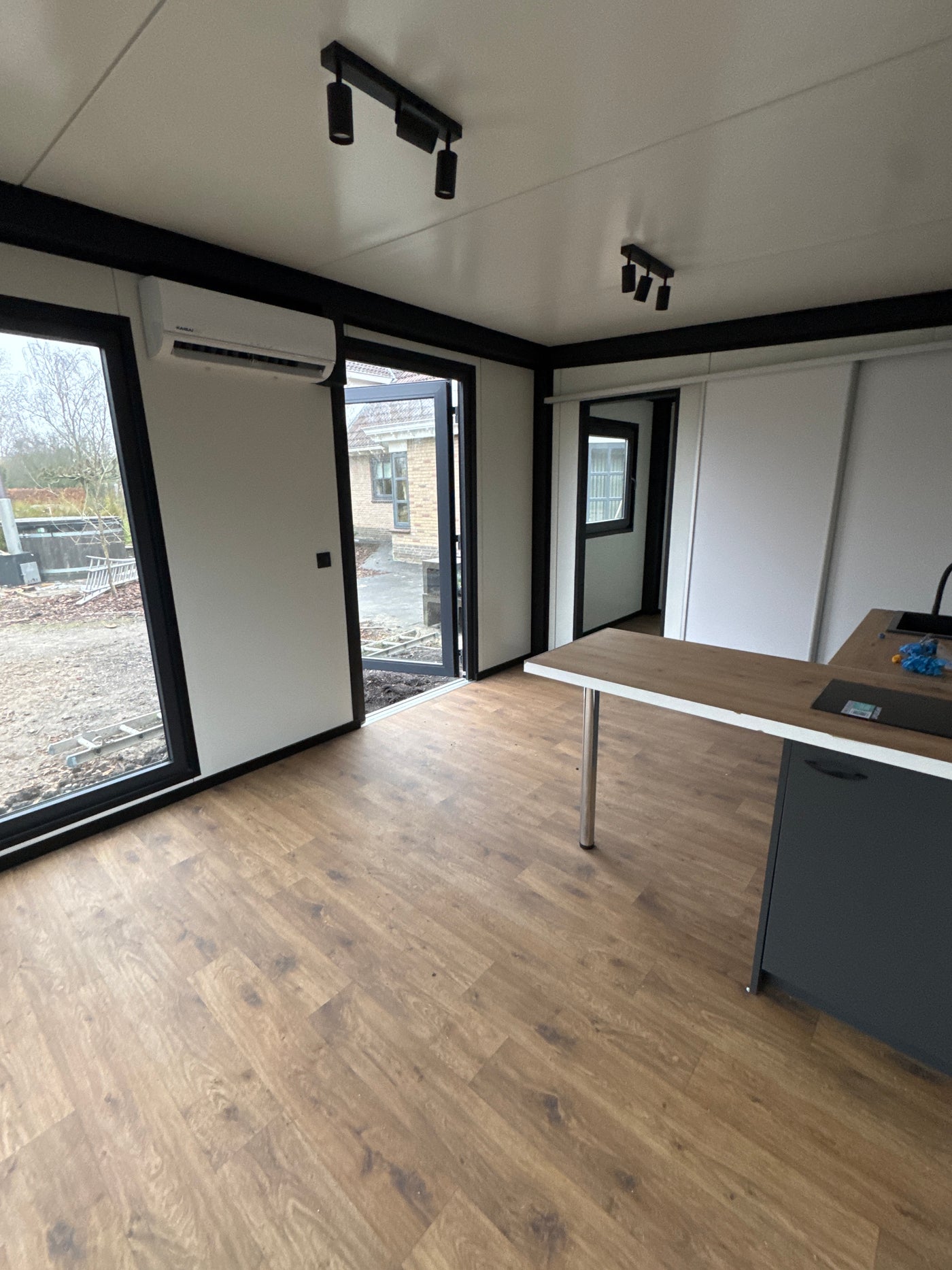 Direct leverbare woonunit van 6,5 × 3,2 meter geplaatst in Buitenpost met slaapkamer, keuken en badkamer