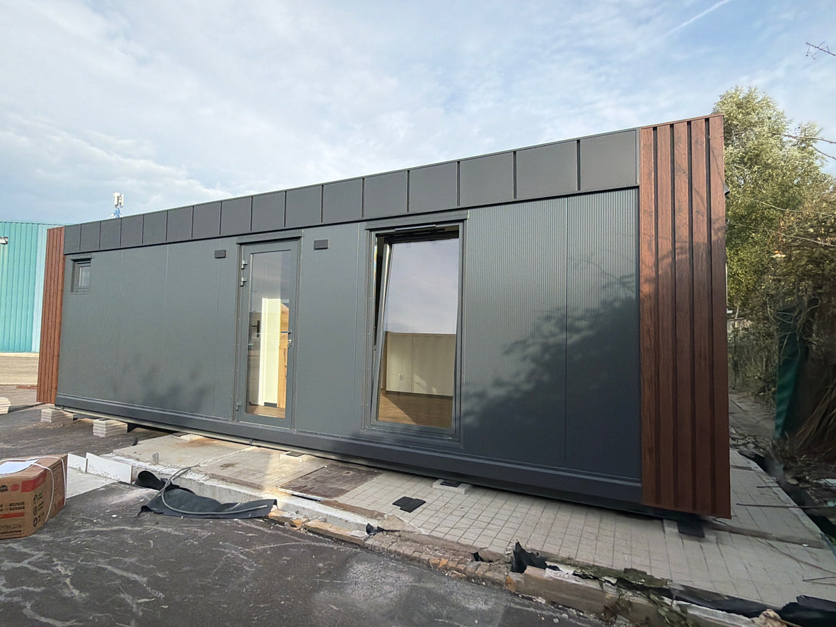 Kantoorunit van 9 × 3,2 meter in Hoogvliet met donkere gevel, houtlook accenten en complete sanitaire voorzieningen